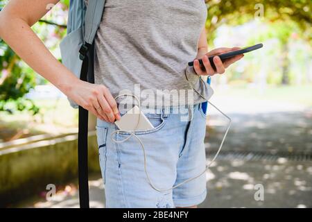 Tragbares Ladegerät in Jeans Tasche der Frau Reisenden mit usb-Kabel zum Aufladen Telefon für die Suche nach Standort im Freien Stockfoto