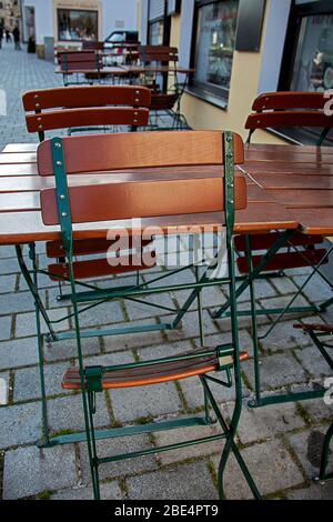 Zusammengefaltete Gartenstühle und leere Tische vor einer Straßenbar Stockfoto