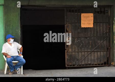 Havanna, Kuba. April 2020. Ein Mann mit Maske ist am 11. April 2020 auf einem Parkplatz in Havanna, Kuba, im Dienst. Die kubanische Regierung hat seit Samstag begonnen, den öffentlichen Verkehr als vorbeugende Maßnahme gegen COVID-19 auszusetzen. Kuba hat Maßnahmen wie die Schließung von Grenzen, die Aussetzung des Transports zwischen den Provinzen und die Schließung von Schulen ergriffen, um die Ausbreitung der Epidemie einzudämmen. Kredit: Zhu Wanjun/Xinhua/Alamy Live News Stockfoto