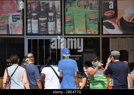 Havanna, Kuba. April 2020. Maskierte Menschen kaufen Lebensmittel am Schaufenster eines Ladens in Havanna, Kuba, 11. April 2020. Die kubanische Regierung hat seit Samstag begonnen, den öffentlichen Verkehr als vorbeugende Maßnahme gegen COVID-19 auszusetzen. Kuba hat Maßnahmen wie die Schließung von Grenzen, die Aussetzung des Transports zwischen den Provinzen und die Schließung von Schulen ergriffen, um die Ausbreitung der Epidemie einzudämmen. Kredit: Zhu Wanjun/Xinhua/Alamy Live News Stockfoto