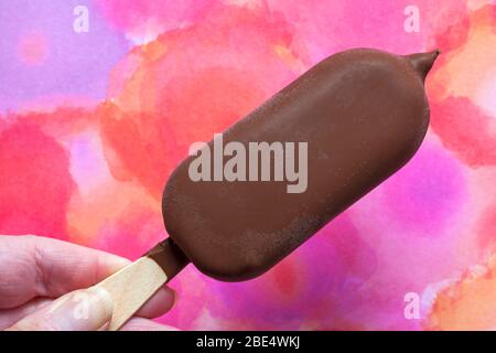 Hand halten Magnum Doppel Kirsche Eis vor bunten Hintergrund - UK Stockfoto