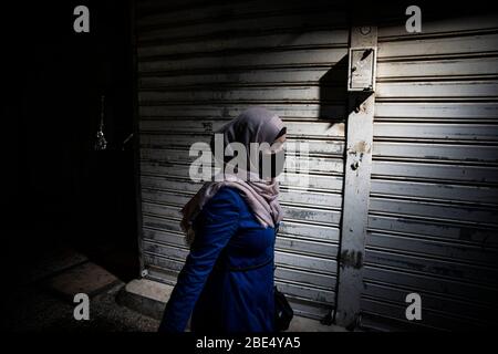 Jerusalem, Israel. April 2020. Eine Frau trägt eine Gesichtsmaske, als sie vor einem geschlossenen Geschäft vorbeigeht. Die israelische Regierung genehmigte eine enge Quarantäne mehrerer Gebiete Jerusalems, einschließlich der historischen Altstadt, um die Ausbreitung des Coronavirus zu verlangsamen. Kredit: Ilia Yefimovich/dpa/Alamy Live News Stockfoto