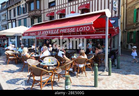 Die Bewohner der Stadt und Touristen entspannen sich in einem Café Le Joinville auf einer Straße im Zentrum von Trouville . Normandie, Frankreich. Stockfoto