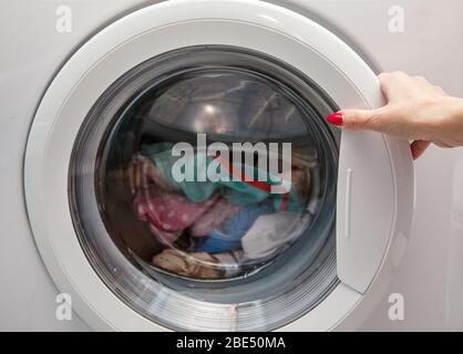 Wäsche wird in die Waschmaschine geladen. Weibliche Handschelle Stockfoto