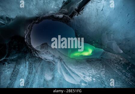 Nordlichter aurora borealis über Gletschereishöhle. Stockfoto