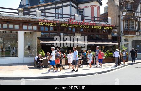 Bewohner der Stadt und Touristen entspannen sich in einem Barbara Restaurant auf einer Straße im Zentrum von Dauville. Normandie, Frankreich. Stockfoto