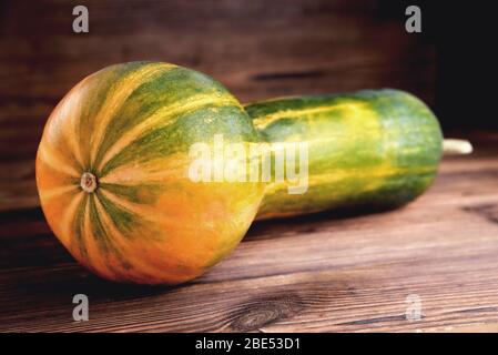 Gelb-grüner länglicher Kürbis, natürlicher Holzhintergrund, Diätnahrung, Halloween Nahaufnahme Stockfoto