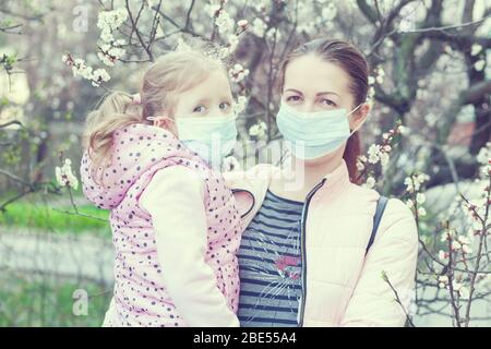 Tochter und Mutter tragen Masken auf der Straße. Pandemievirus. Stockfoto