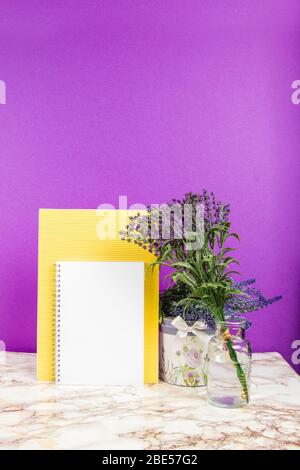 Leeres gelbes Papier mit Lavendelblüten auf einem violetten Hintergrund Stockfoto