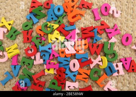 Mehrfarbige Holzbuchstaben in rot, grün, blau, pink & gelb. Die Buchstaben sind ein Spielzeug für Kinder und sind auf dem Boden verstreut. Sie sind eine lustige Art, zu Stockfoto