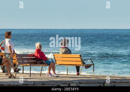 Las Americas,Tenerife, Spanien - 21. Januar 2020: Menschen am Wasser, Spaziergänge auf der Promenade und Entspannung auf Bänken am Meer am blauen Himmel Stockfoto