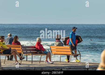 Las Americas,Tenerife, Spanien - 21. Januar 2020: Menschen am Wasser, Spaziergänge auf der Promenade und Entspannung auf Bänken am Meer am blauen Himmel Stockfoto