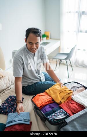 asian Mann setzen ihre Kleidung in den Koffer vor gehen in den Urlaub Stockfoto