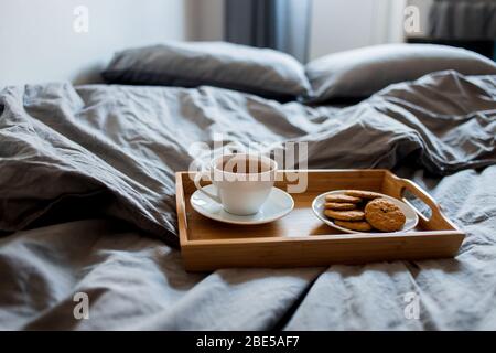 Ein köstliches Frühstück wird jeden Morgen serviert. Eine heiße Tasse Tee und Ingwer Kekse in einem Fach auf eine graue Decke Stockfoto