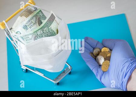 Einkaufswagen in einer Anti-Maske. Polnisches Geld. Hand in einen Gummihandschuh mit Münzen. Das Konzept der Inflation, die durch die Coronavirus-Epidemie verursacht wird Stockfoto