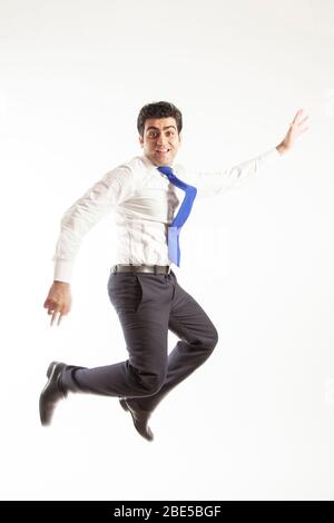 Junger Bürokorporative Mann springen hoch seine Arme mit Freude tragen blaue Krawatte auf einem weißen Hintergrund isoliert Stockfoto