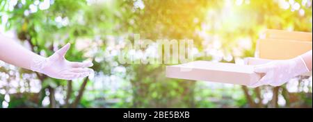 Lieferer hält Boxen mit Gummihandschuhen. Online-Shopping und kostenlose Lieferung nach Hause. Soziale Distanz und zu Hause bleiben sicher bleiben. Stockfoto