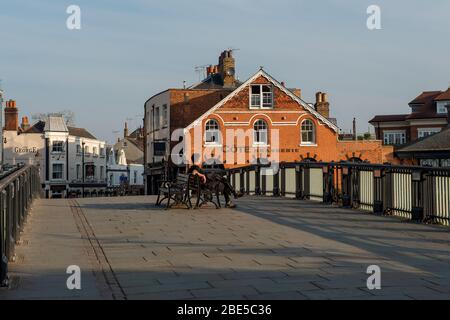 Eton, Windsor, Großbritannien. April 2020. Ein Mann sitzt auf einem Sitz auf einer ansonsten menschenleeren Windsor Bridge. Kredit: Maureen McLean/Alamy Live News Stockfoto