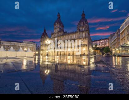 A Coruna, Spanien. Blick auf Praza de Maria Pita Platz mit Gebäude des Rathauses spiegelt sich in Pfütze in der Dämmerung Stockfoto