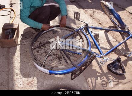 Ein indischer Radmechaniker, der einen Zyklusdurchstich fixiert Stockfoto