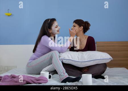 Junge Frau, die Gesichtsruck auf das Gesicht ihrer Schwester aufwendet. Stockfoto