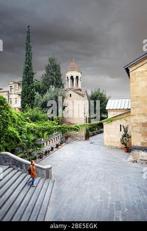 Touristische Frau in braunen Sakko Spaziergang durch die alten Straßen in der Nähe von sioni Kathedrale im Zentrum von Tiflis, Georgien Stockfoto