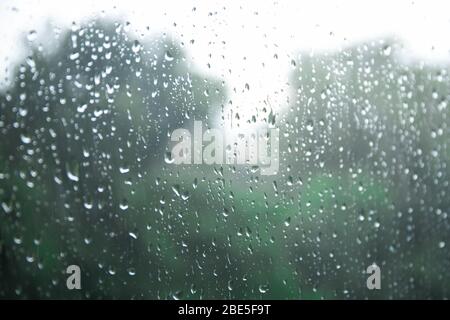 Regentropfen auf einer Fensterscheibe auf dem Hintergrund eines stürmischen Himmels. Stockfoto