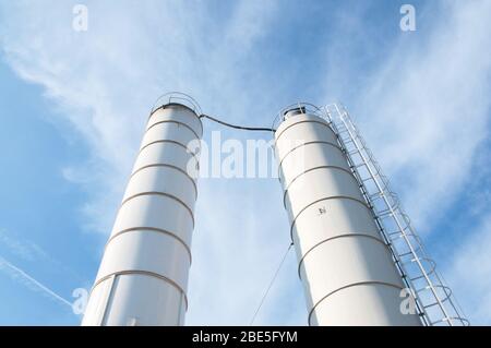 Silo zur Lagerung von Zement. Zementfabrik Maschinen an einem klaren blauen Tag. Teil einer Betonanlage. Lagerung von Materialien bei der Betonherstellung Stockfoto