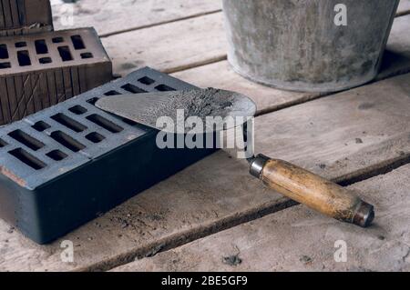 Ein Maurer-Tool durch einen strengen Plan am Arbeitsplatz. Kelle für Maurerlegung. Bau Maurer Zement Mörtel Werkzeuge. Stockfoto