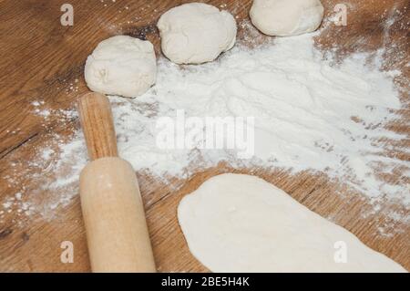 Nudelholz, Teig und Mehl auf dem Tisch. Der Prozess der Herstellung von hausgemachten Kuchen. Hausgemachtes Backen. Kochen von zu Hause Teig. Stockfoto