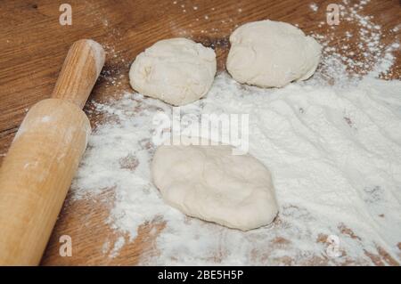 Nudelholz, Teig und Mehl auf dem Tisch. Der Prozess der Herstellung von hausgemachten Kuchen. Hausgemachtes Backen. Kochen von zu Hause Teig. Stockfoto