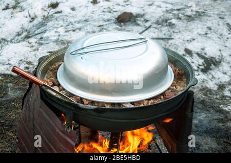 Das Fleisch wird in einem Kessel auf Feuer gekocht. Kochen ein Nationalgericht. Stockfoto