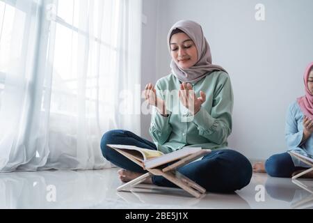 Verschleierte junge Frauen beten zusammen nach dem Studium des Korans im Raum Stockfoto