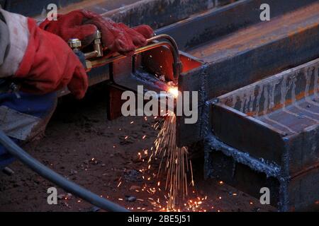 Schneiden eines Stahlträgers mit einem Gasbrenner. Industrielle Metallbearbeitung. Der Prozess der Vorbereitung eines Stahlträgers für die Installation. Stockfoto