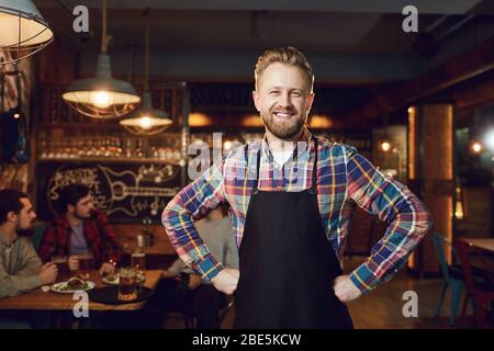 Bärtige lächelnd Barkeeper, Kellner, die auf dem Hintergrund einer Bar. Stockfoto