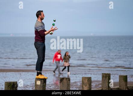 Portobello, Edinburgh. Schottland, Großbritannien. 12 April 2020. Ostersonntagnachmittag bei sonnigem Wetter trainieren und wandern die Besucher am Strand von Portobello. Der beliebte Strand und die Promenade sind sehr ruhig und die Leute üben meist eine richtige soziale Distanz aus. Abgebildet; Mann jongliert am portobello Beach. Iain Masterton/Alamy Live News Stockfoto