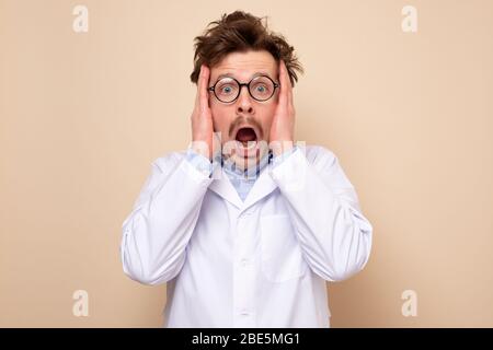 Lustige Wissenschaftler junger Mann in Brille und weißem Mantel ist mit Nachrichten überrascht. Stockfoto