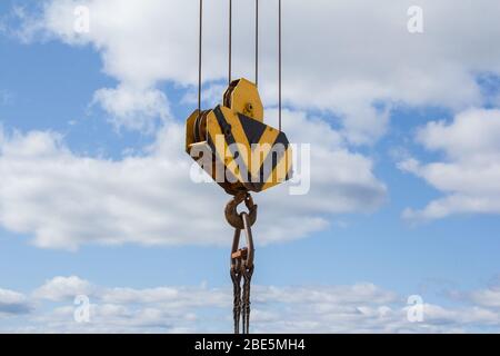 Haken eines großen Baukran gegen den blauen Himmel. Teil des Mechanismus zum Heben schwerer Lasten auf einer Baustelle Stockfoto
