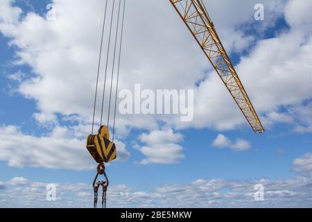 Haken eines großen Baukran gegen den blauen Himmel. Teil des Mechanismus zum Heben schwerer Lasten auf einer Baustelle Stockfoto