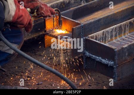 Schneiden eines Stahlträgers mit einem Gasbrenner. Industrielle Metallbearbeitung. Der Prozess der Vorbereitung eines Stahlträgers für die Installation. Stockfoto