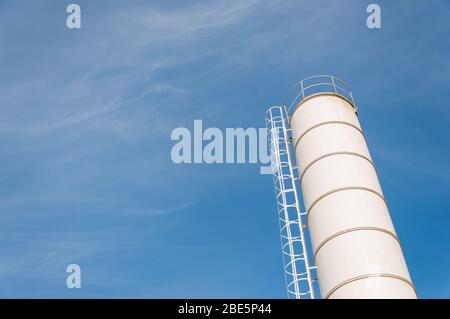 Silo zur Lagerung von Zement. Zementfabrik Maschinen an einem klaren blauen Tag. Teil einer Betonanlage. Lagerung von Materialien bei der Betonherstellung Stockfoto