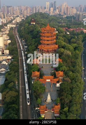 Wuhan, China. April 2020. Luftaufnahme vom 12. April 2020 zeigt einen Hochgeschwindigkeitszug, der am Gelben Kranturm oder Huanghelou, einem Wahrzeichen der Stadt Wuhan, der zentralen Provinz Hubei, fährt. Kredit: Zhao Jun/Xinhua/Alamy Live News Stockfoto