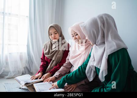 Drei muslimische asiaten lesen und lernen das heilige Buch des Al-Quran zusammen auf dem Boden im Raum sitzen Stockfoto