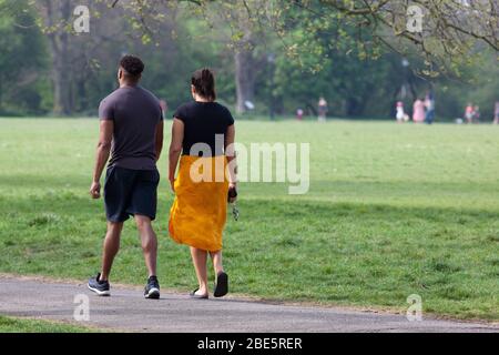 London, Großbritannien, 12. April 2020: Am Ostersonntag beobachten Menschen die sozialen Distanzierungsregeln, während sie am Clapham Common Bewegung und frische Luft in der Sonne nehmen. Anna Watson/ Alamy Live News Stockfoto