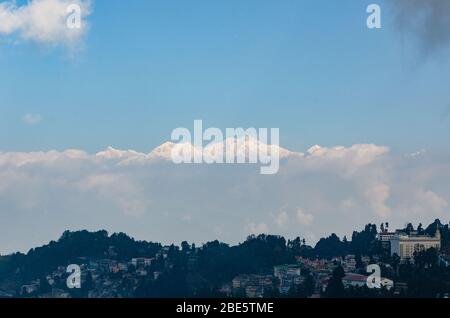 Schöne Aussicht auf das Kangchendzönga-Massiv, das sich an einem teilweise bewölkten Wintermorgen in Darjeeling, Westbengalen, Indien über tief liegende Wolken erhebt Stockfoto