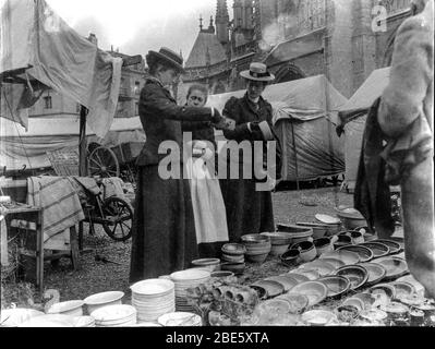 Zwei gut gekleidete reiche Frauen kaufen in den 1890er Jahren an einem Marktstand auf dem Marktplatz von Dieppe in der Normandie, Frankreich, ein Stockfoto