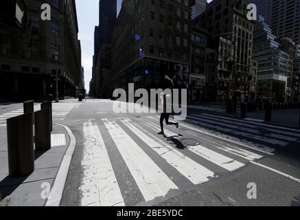 New York, USA. April 2020. Eine Frau mit einer Schutzmaske joggt auf einer ruhigen 5th Avenue, während Kardinal Timothy Dolan am Sonntag, den 12. April 2020, eine Ostermesse in der leeren St. Patrick's Cathedral in New York City anbietet. Zum ersten Mal haben die US-Regierung und Präsident Trump alle 50 Staaten für ein und dasselbe Ereignis zu einer großen Katastrophe erklärt. Foto von John Angelillo/UPI Quelle: UPI/Alamy Live News Stockfoto