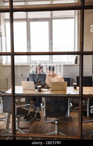 Bild eines jungen Kollegen, der im Büro mit einem Laptop arbeitet. Stockfoto