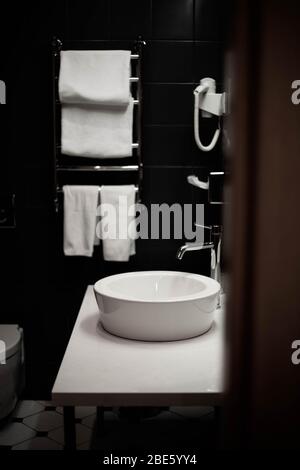 Badezimmer im Hotel. Weiße Handtücher und weißes Waschbecken. Stockfoto