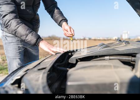 Der Fahrer überprüft den Ölstand im Fahrzeug auf unverschuldet befahrter Straße Stockfoto